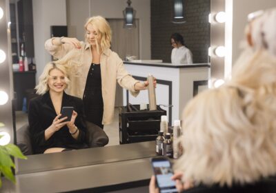 blonde-woman-with-mobile-phone-getting-her-hair-done-min